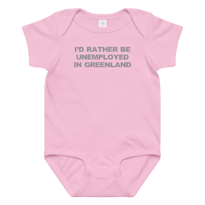 "I'd rather be unemployed in greenland" printed on a pink baby jersey bodysuit laying on a flat surface amongst other clothes