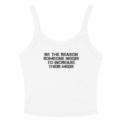 "Be the reason someone needs to increase their meds" printed on a solid white blend women's micro-rib tanktop laying on a flat surface amongst sunglasses and shorts