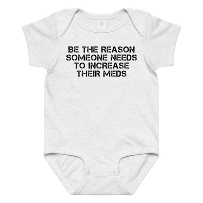 "Be the reason someone needs to increase their meds" printed on a ash baby jersey bodysuit laying on a flat surface amongst other clothes