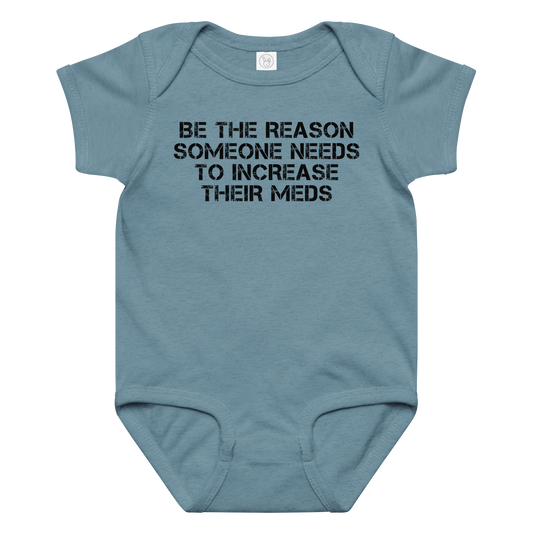 "Be the reason someone needs to increase their meds" printed on a vintage indigo baby jersey bodysuit laying on a flat surface amongst other clothes