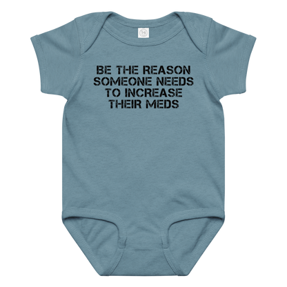 "Be the reason someone needs to increase their meds" printed on a vintage indigo baby jersey bodysuit laying on a flat surface amongst other clothes