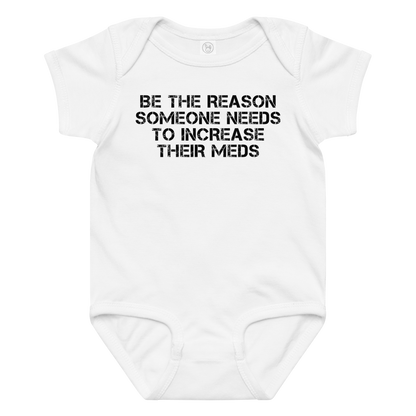 "Be the reason someone needs to increase their meds" printed on a white baby jersey bodysuit laying on a flat surface amongst other clothes