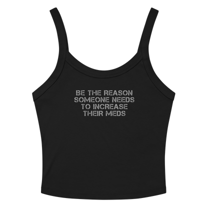 "Be the reason someone needs to increase their meds" printed on a solid black blend women's micro-rib tanktop laying on a flat surface amongst sunglasses and shorts