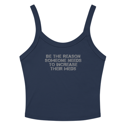 "Be the reason someone needs to increase their meds" printed on a solid navy blend women's micro-rib tanktop laying on a flat surface amongst sunglasses and shorts