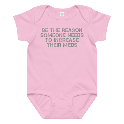 "Be the reason someone needs to increase their meds" printed on a pink baby jersey bodysuit laying on a flat surface amongst other clothes