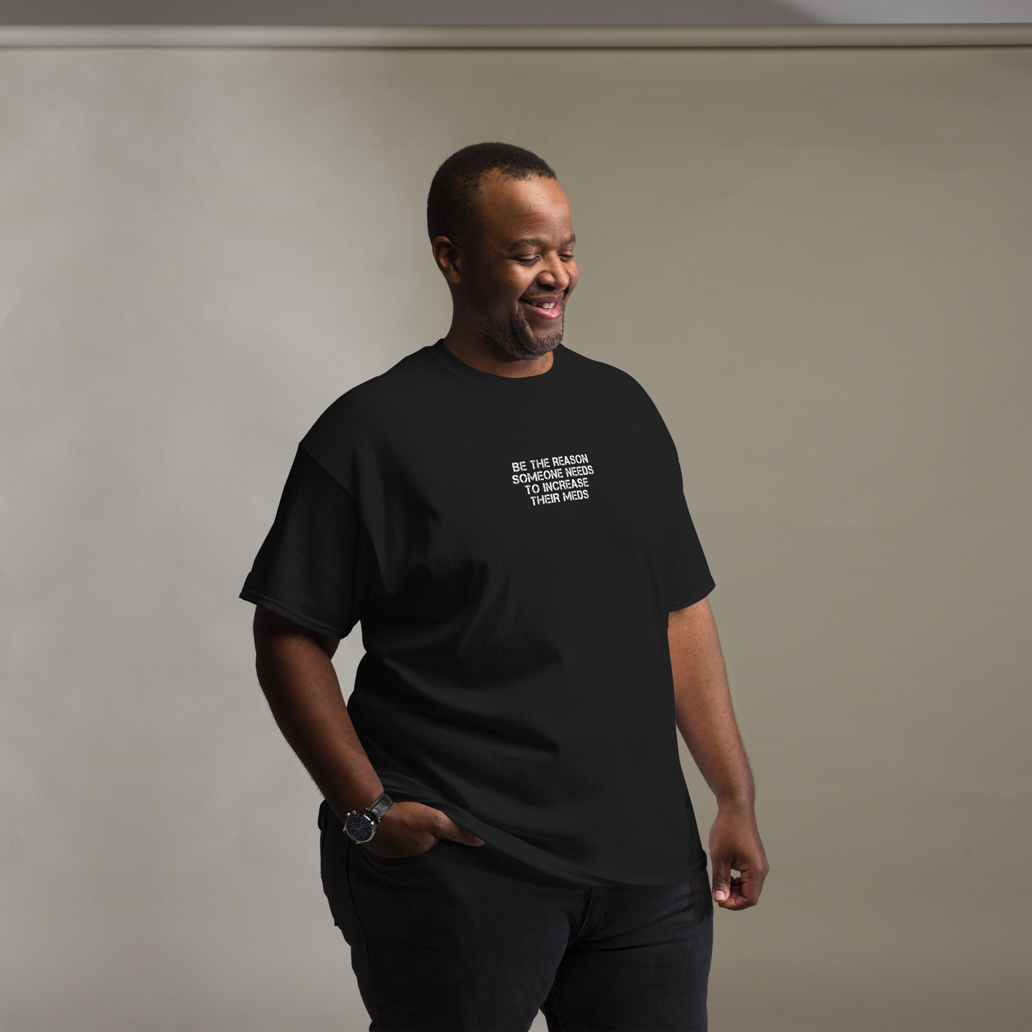 "Be the reason someone needs to increase their meds" printed on a black unisex classic tee worn by a male