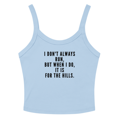"I don't always run, but when I do, it is for the hills." printed on a solid baby blue blend women's micro-rib tanktop laying on a flat surface amongst sunglasses and shorts