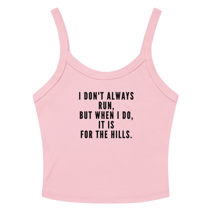 "I don't always run, but when I do, it is for the hills." printed on a solid pink blend women's micro-rib tanktop laying on a flat surface amongst sunglasses and shorts