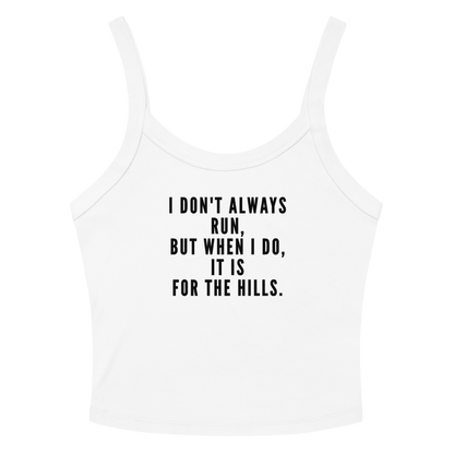 "I don't always run, but when I do, it is for the hills." printed on a solid white blend women's micro-rib tanktop laying on a flat surface amongst sunglasses and shorts