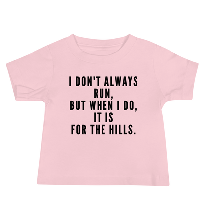"I don't always run, but when I do, it is for the hills." printed on a pink baby jersey short sleeve tee laying on a flat surface
