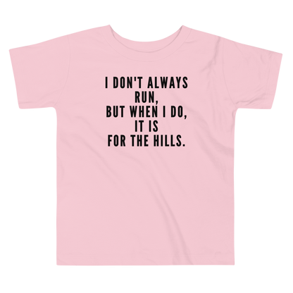 "I don't always run, but when I do, it is for the hills." printed on a pink toddler short sleeve tee laying on a flat surface