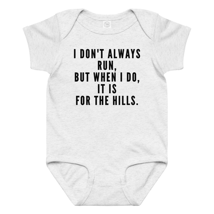 "I don't always run, but when I do, it is for the hills." printed on a ash baby jersey bodysuit laying on a flat surface amongst other clothes