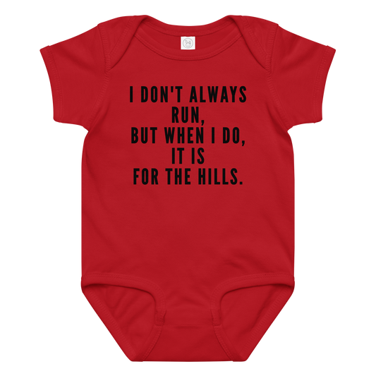 "I don't always run, but when I do, it is for the hills." printed on a red baby jersey bodysuit laying on a flat surface amongst other clothes