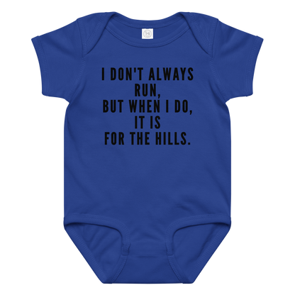 "I don't always run, but when I do, it is for the hills." printed on a royal baby jersey bodysuit laying on a flat surface amongst other clothes