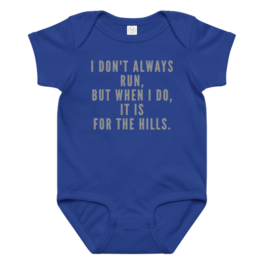 "I don't always run, but when I do, it is for the hills." printed on a royal baby jersey bodysuit laying on a flat surface amongst other clothes