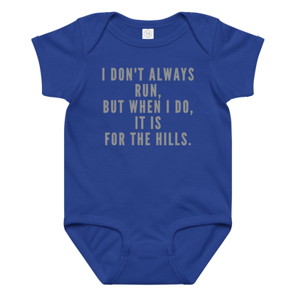 "I don't always run, but when I do, it is for the hills." printed on a royal baby jersey bodysuit laying on a flat surface amongst other clothes