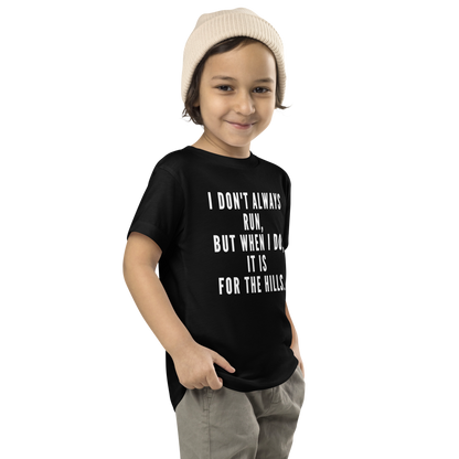 "I don't always run, but when I do, it is for the hills." printed on a black toddler short sleeve tee worn by a male who is also wearing a knit cap