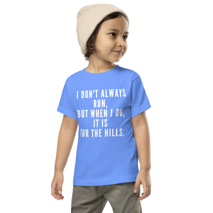 "I don't always run, but when I do, it is for the hills." printed on a heather columbia blue toddler short sleeve tee worn by a male wearing a cap