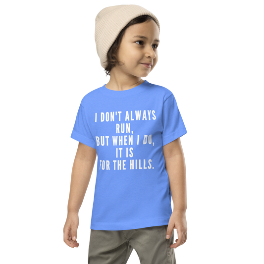 "I don't always run, but when I do, it is for the hills." printed on a heather columbia blue toddler short sleeve tee worn by a male wearing a cap