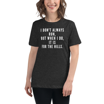 "I don't always run, but when I do, it is for the hills." printed on a dark grey heather women's relaxed t-shirt worn by a female