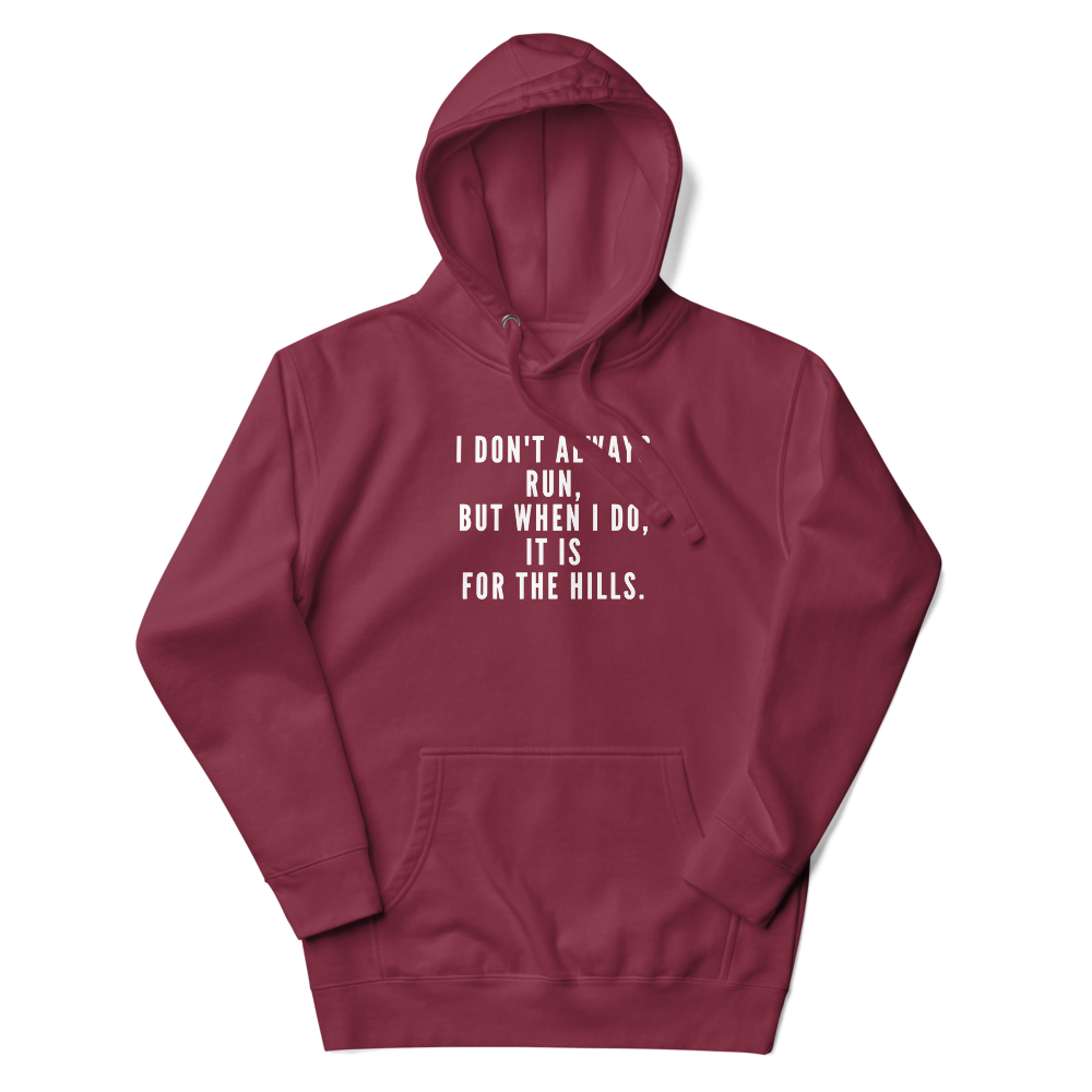 "I don't always run, but when I do, it is for the hills." printed on a maroon unisex hoodie laying on a flat surface with the hood up