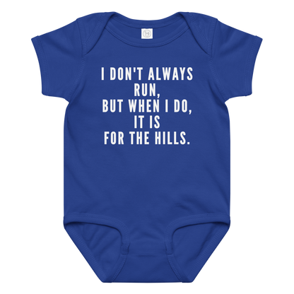 "I don't always run, but when I do, it is for the hills." printed on a royal baby jersey bodysuit laying on a flat surface amongst other clothes