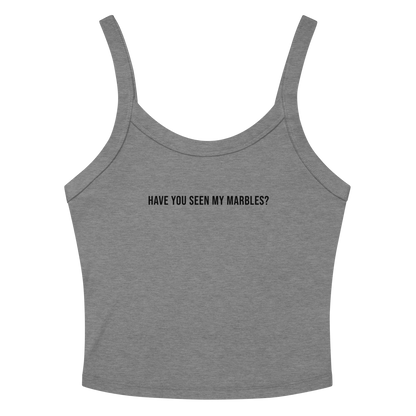"Have you seen my marbles?" printed on a athletic heather women's micro-rib tanktop laying on a flat surface amongst sunglasses and shorts