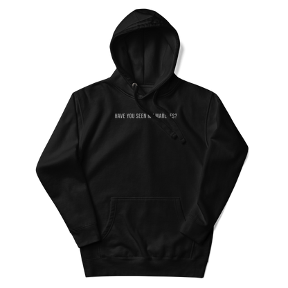 "Have you seen my marbles?" printed on a black unisex hoodie laying on a flat surface with the hood up