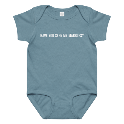 "Have you seen my marbles?" printed on a vintage indigo baby jersey bodysuit laying on a flat surface amongst other clothes