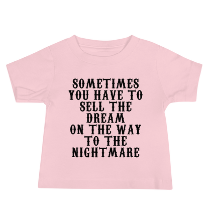 "Sometimes you have to sell the dream on the way to the nightmare" printed on a pink baby jersey short sleeve tee laying on a flat surface