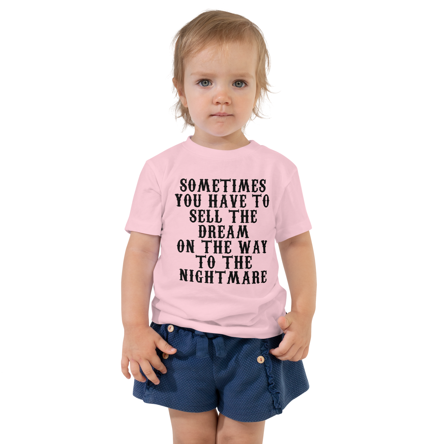 "Sometimes you have to sell the dream on the way to the nightmare" printed on a pink toddler short sleeve tee worn by a female