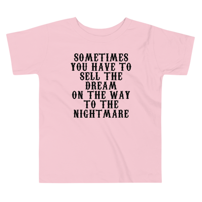 "Sometimes you have to sell the dream on the way to the nightmare" printed on a pink toddler short sleeve tee laying on a flat surface