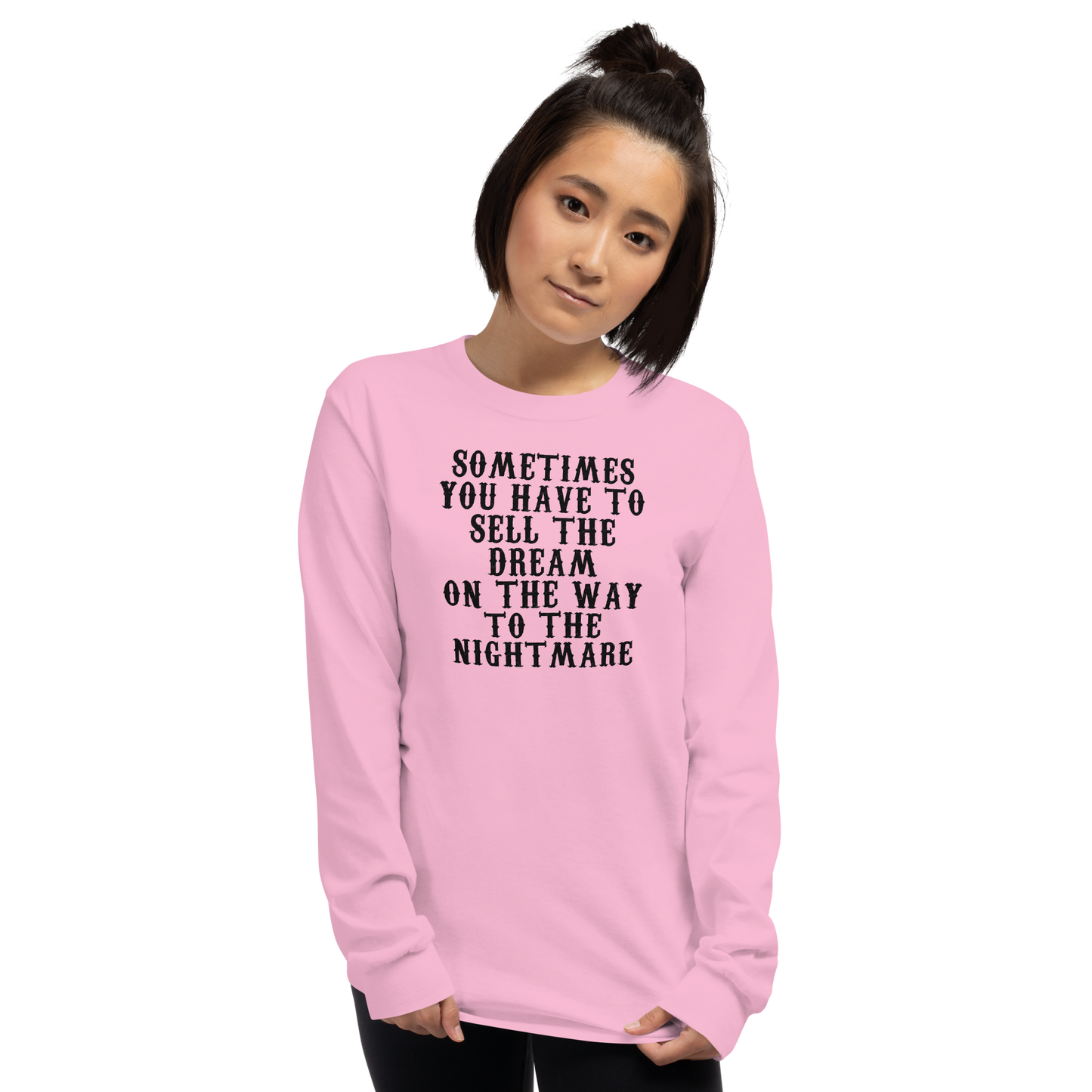 "Sometimes you have to sell the dream on the way to the nightmare" printed on a light pink men's long sleeve shirt worn by a female