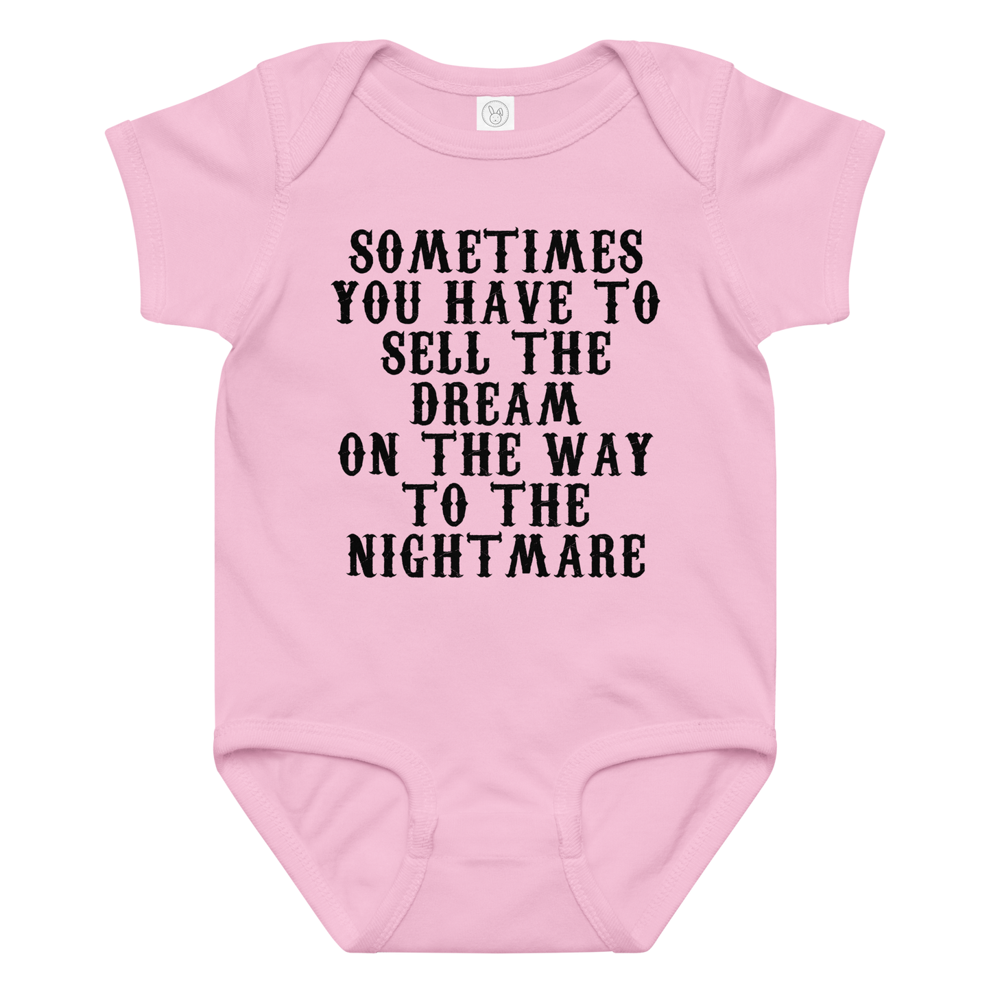 "Sometimes you have to sell the dream on the way to the nightmare" printed on a pink baby jersey bodysuit laying on a flat surface amongst other clothes