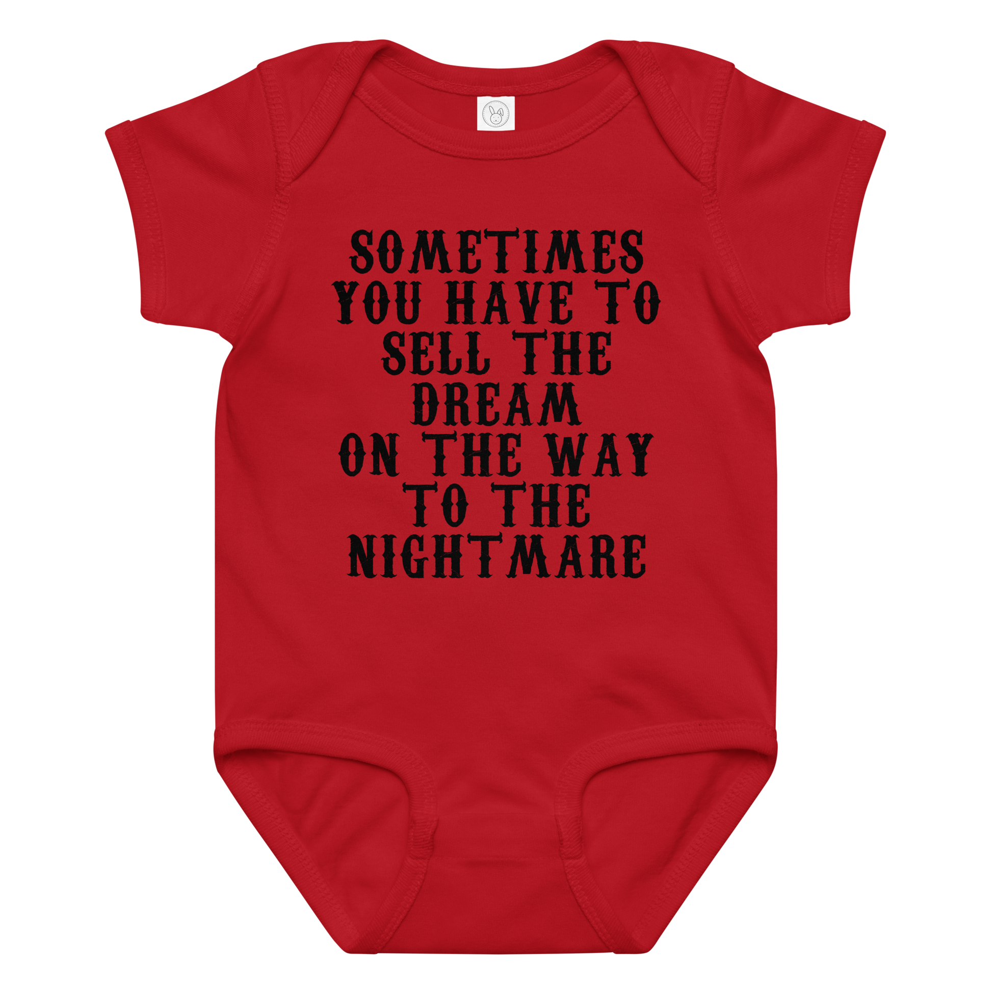 "Sometimes you have to sell the dream on the way to the nightmare" printed on a red baby jersey bodysuit laying on a flat surface amongst other clothes