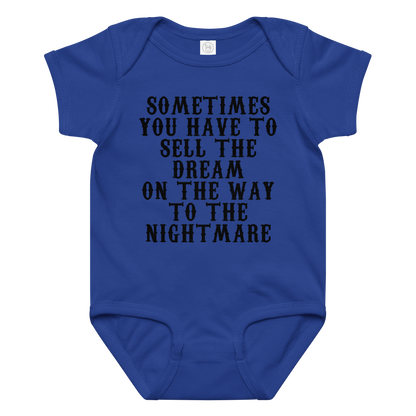 "Sometimes you have to sell the dream on the way to the nightmare" printed on a royal baby jersey bodysuit laying on a flat surface amongst other clothes