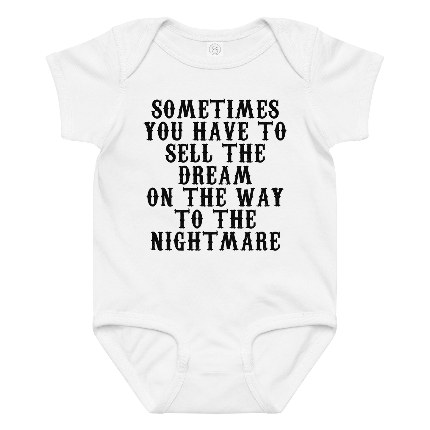 "Sometimes you have to sell the dream on the way to the nightmare" printed on a white baby jersey bodysuit laying on a flat surface amongst other clothes