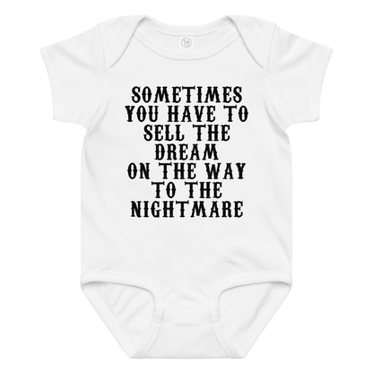 "Sometimes you have to sell the dream on the way to the nightmare" printed on a white baby jersey bodysuit laying on a flat surface amongst other clothes