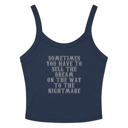 "Sometimes you have to sell the dream on the way to the nightmare" printed on a solid navy blend women's micro-rib tanktop laying on a flat surface amongst sunglasses and shorts
