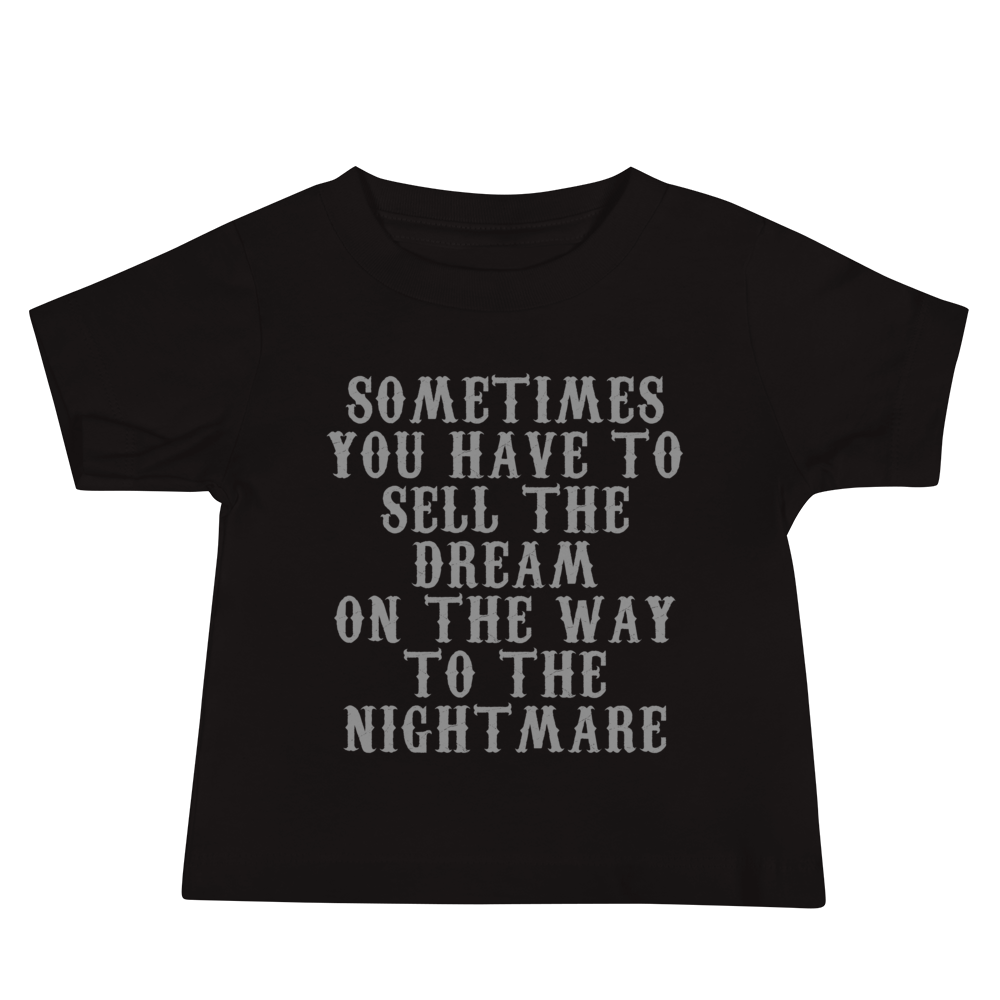 "Sometimes you have to sell the dream on the way to the nightmare" printed on a black baby jersey short sleeve tee laying on a flat surface
