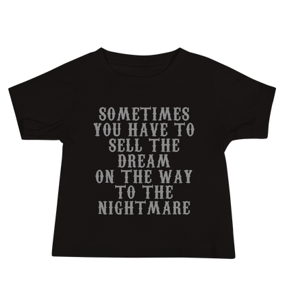 "Sometimes you have to sell the dream on the way to the nightmare" printed on a black baby jersey short sleeve tee laying on a flat surface