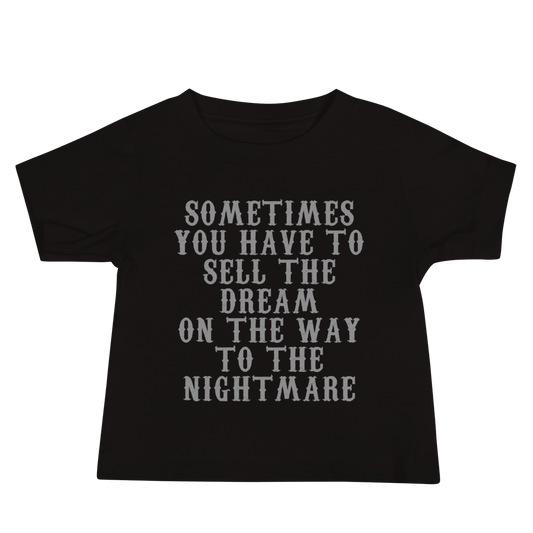 "Sometimes you have to sell the dream on the way to the nightmare" printed on a black baby jersey short sleeve tee laying on a flat surface