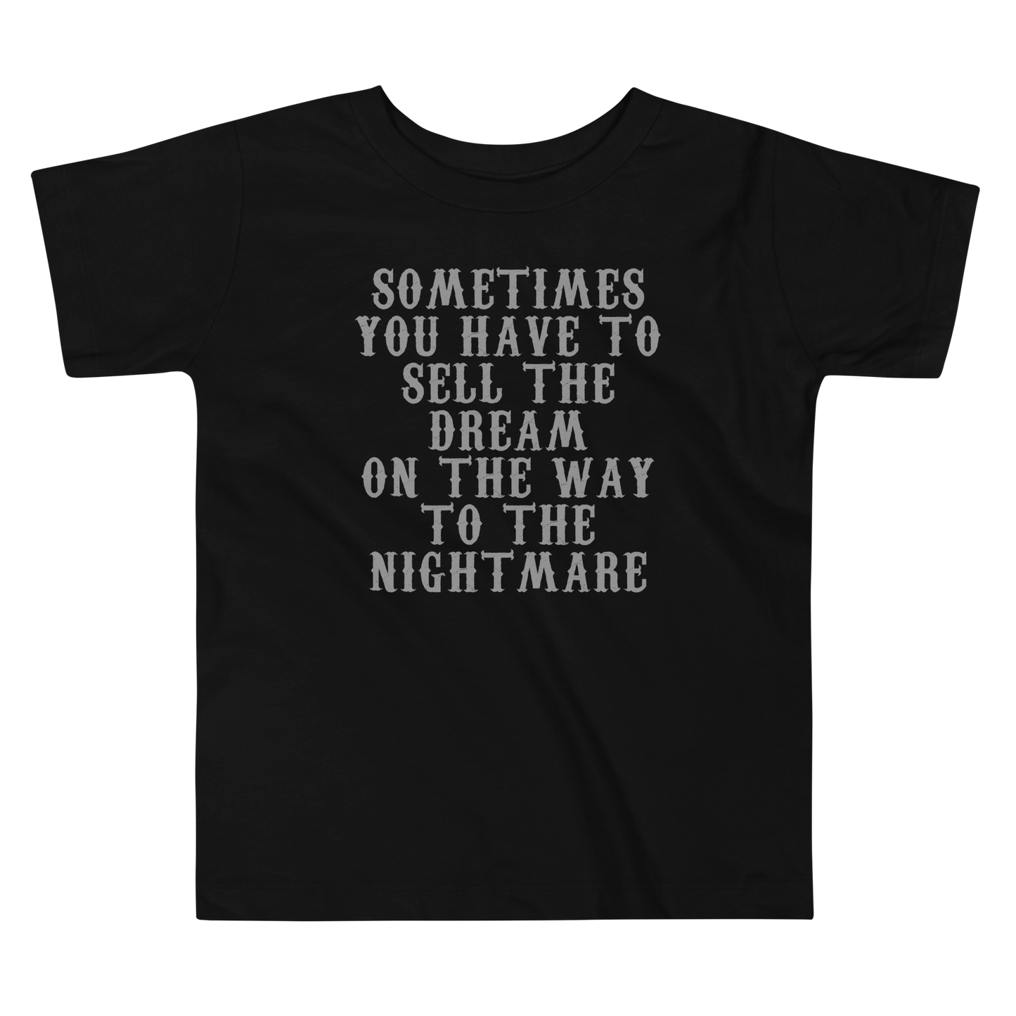 "Sometimes you have to sell the dream on the way to the nightmare" printed on a black toddler short sleeve tee laying on a flat surface