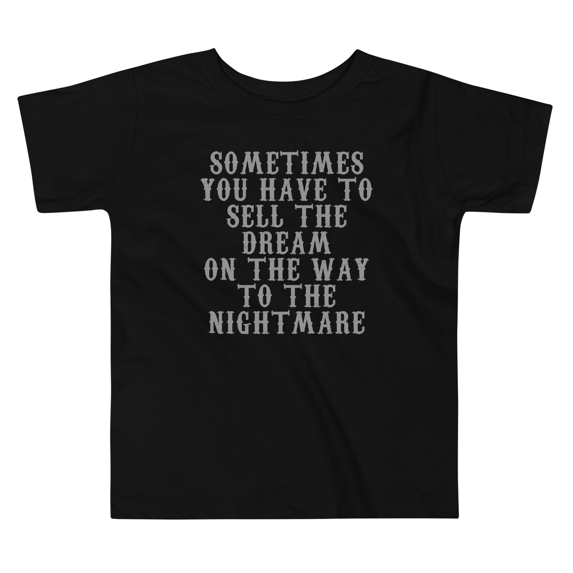 "Sometimes you have to sell the dream on the way to the nightmare" printed on a black toddler short sleeve tee laying on a flat surface