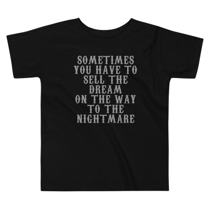 "Sometimes you have to sell the dream on the way to the nightmare" printed on a black toddler short sleeve tee laying on a flat surface