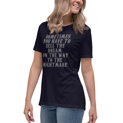 "Sometimes you have to sell the dream on the way to the nightmare" printed on a navy women's relaxed t-shirt worn by a female
