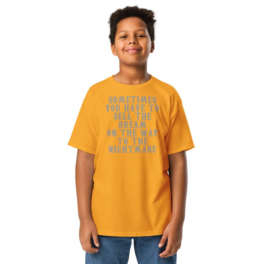"Sometimes you have to sell the dream on the way to the nightmare" printed on a gold youth classic tee worn by a male