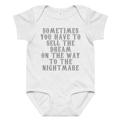 "Sometimes you have to sell the dream on the way to the nightmare" printed on a ash baby jersey bodysuit laying on a flat surface amongst other clothes