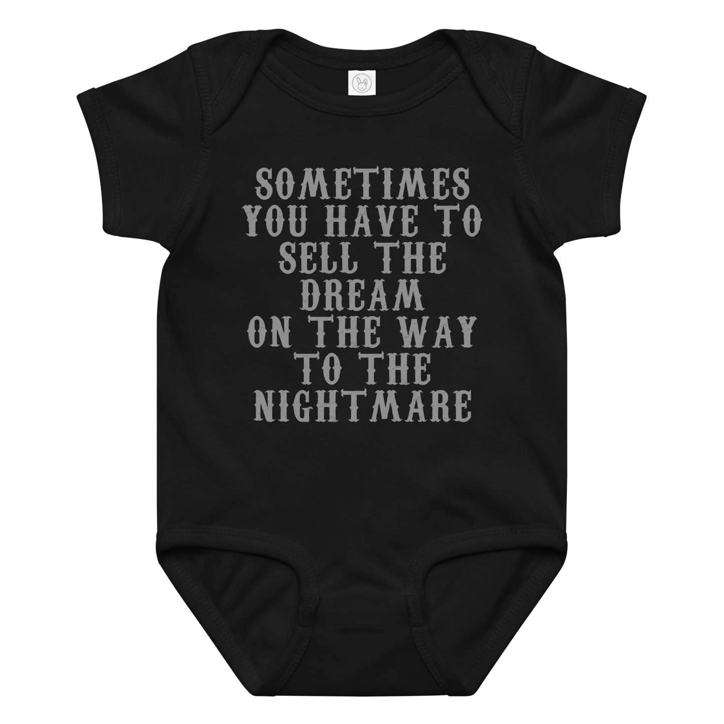 "Sometimes you have to sell the dream on the way to the nightmare" printed on a black baby jersey bodysuit laying on a flat surface amongst other clothes