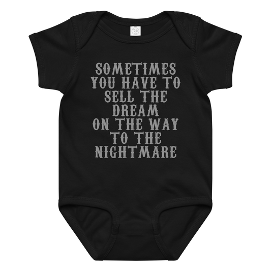 "Sometimes you have to sell the dream on the way to the nightmare" printed on a black baby jersey bodysuit laying on a flat surface amongst other clothes